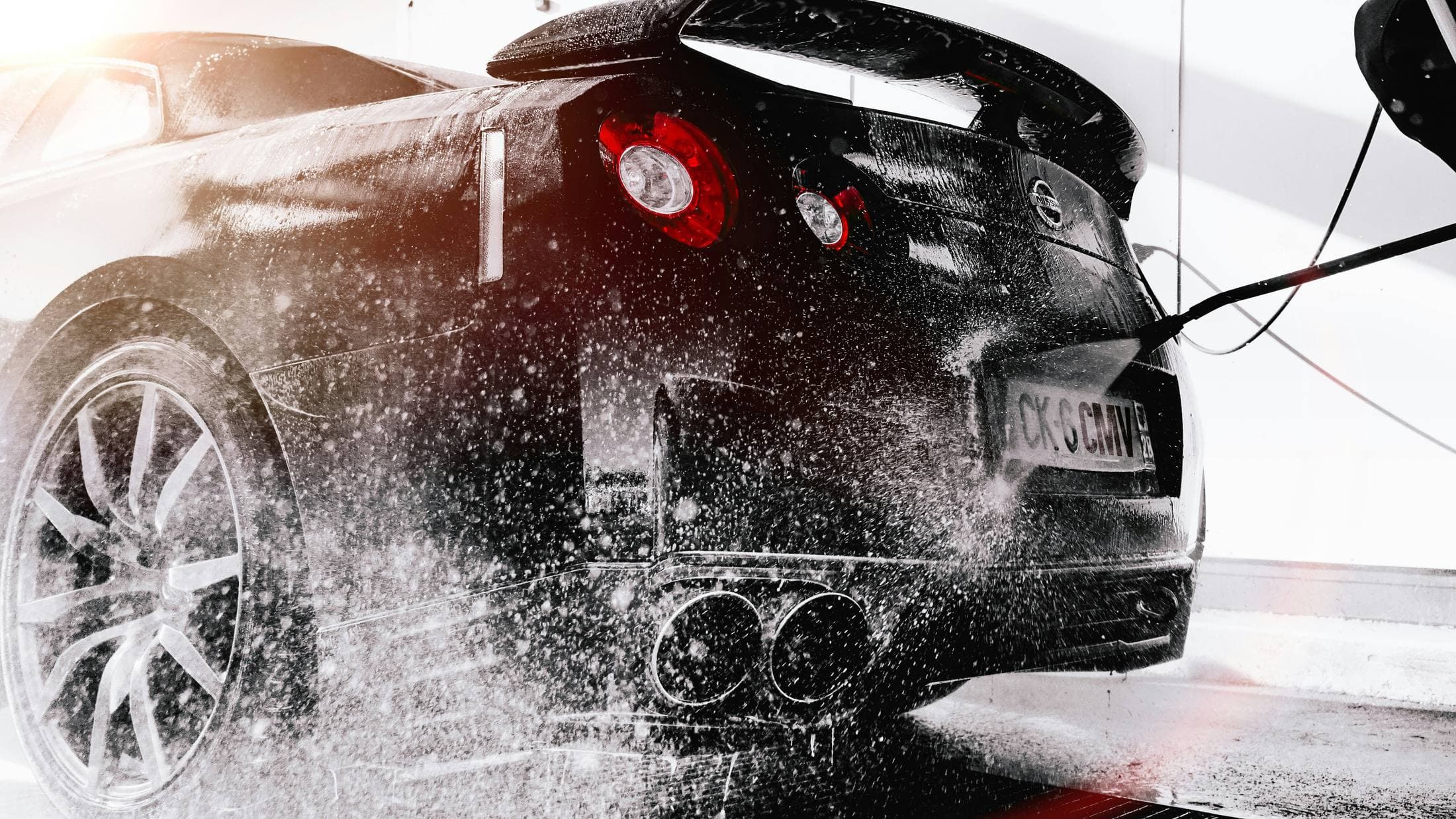 Black luxury sports car being detailed under studio lighting